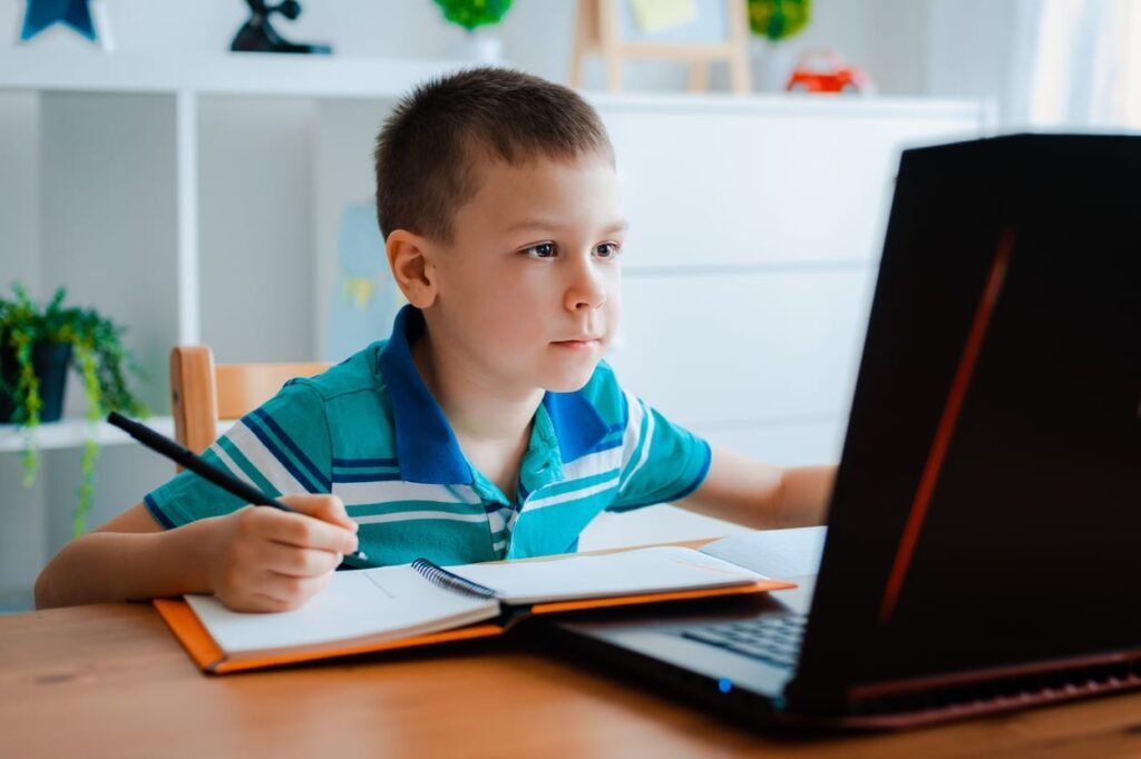 Child focusing on his homework on computer.